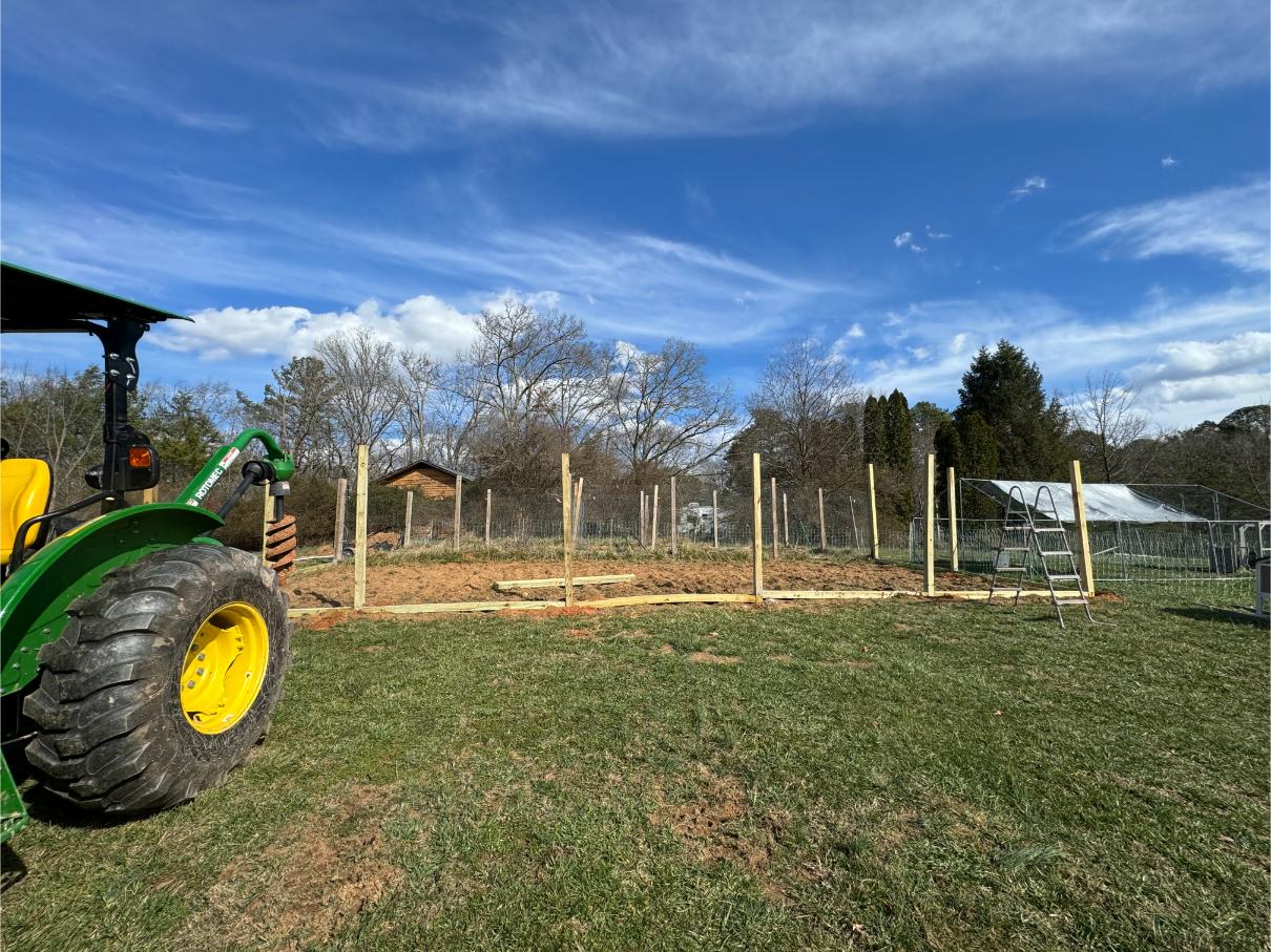 A farm scene with a tractor and fencing under a partly cloudy sky.