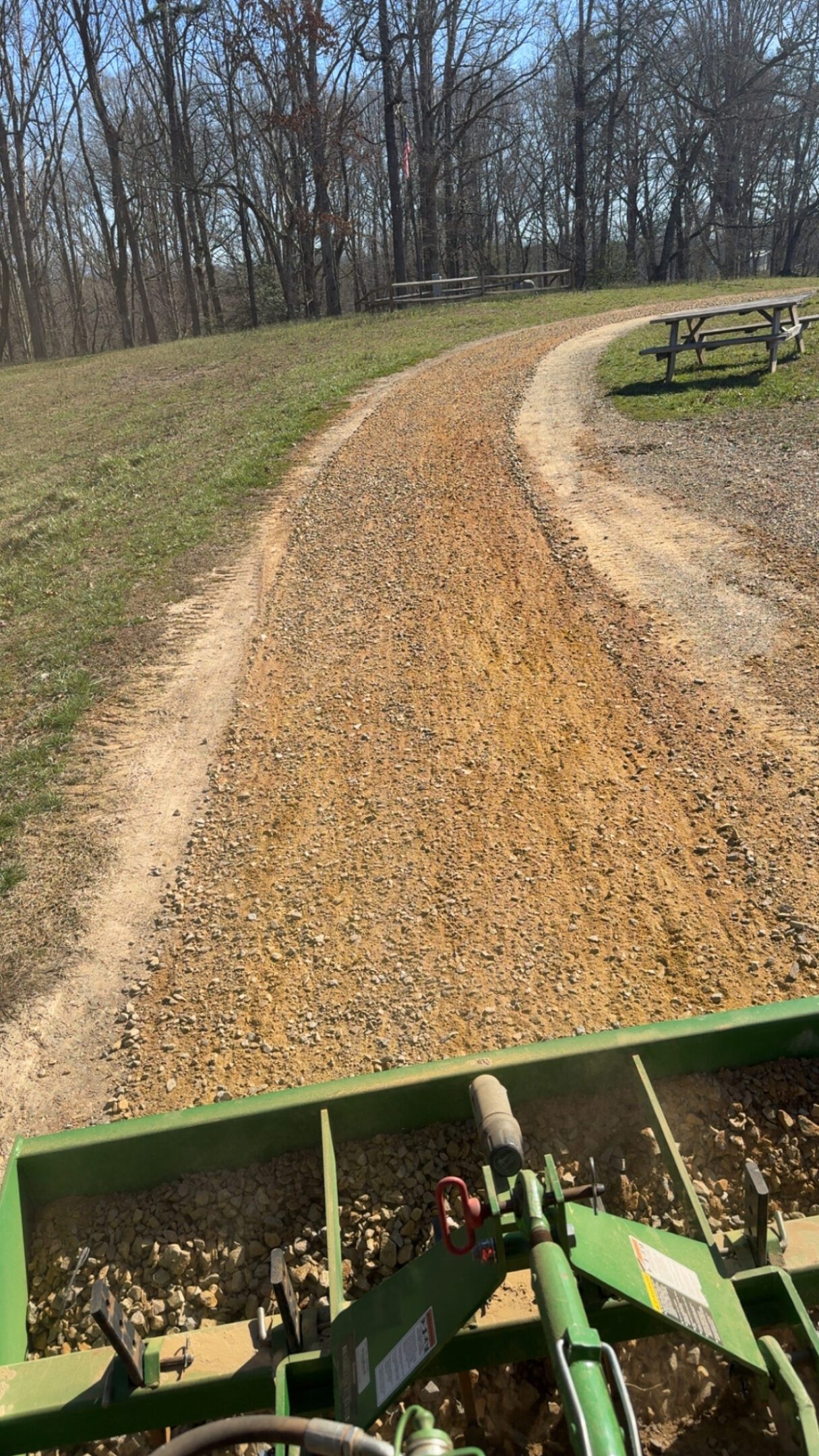 A newly laid gravel path curving through a grassy area near a picnic table.