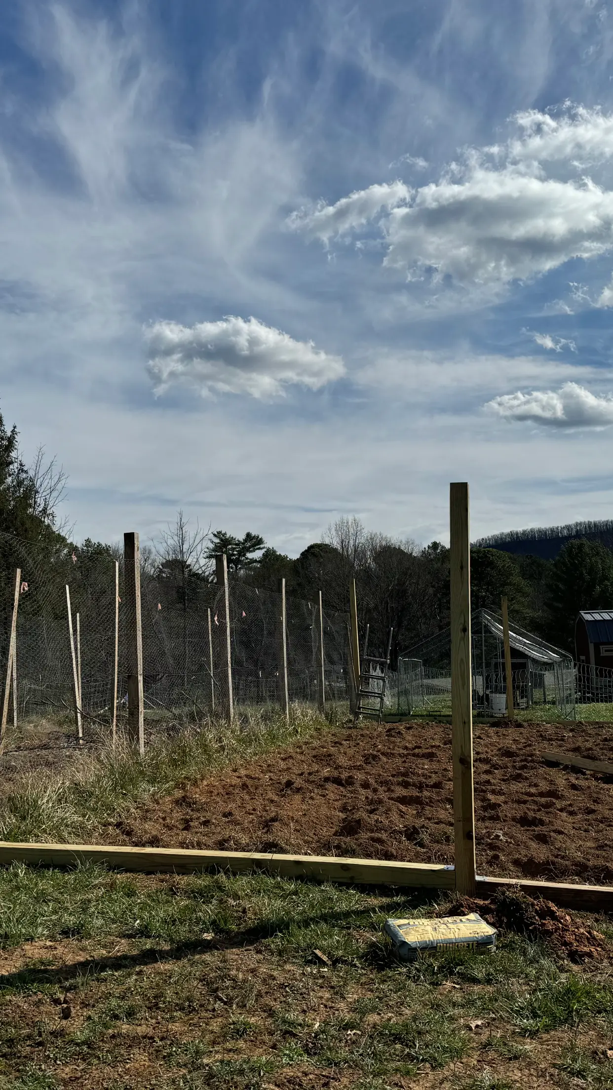 A rural fence line under a cloudy sky with distant hills.