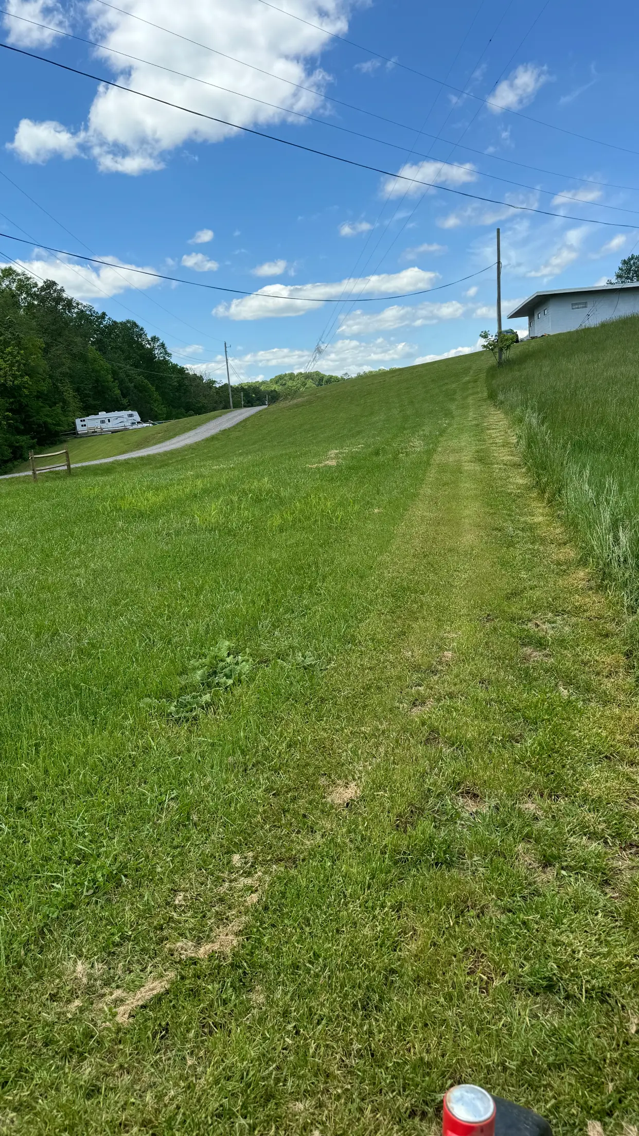A grassy hill with a narrow mowed path under a blue sky.