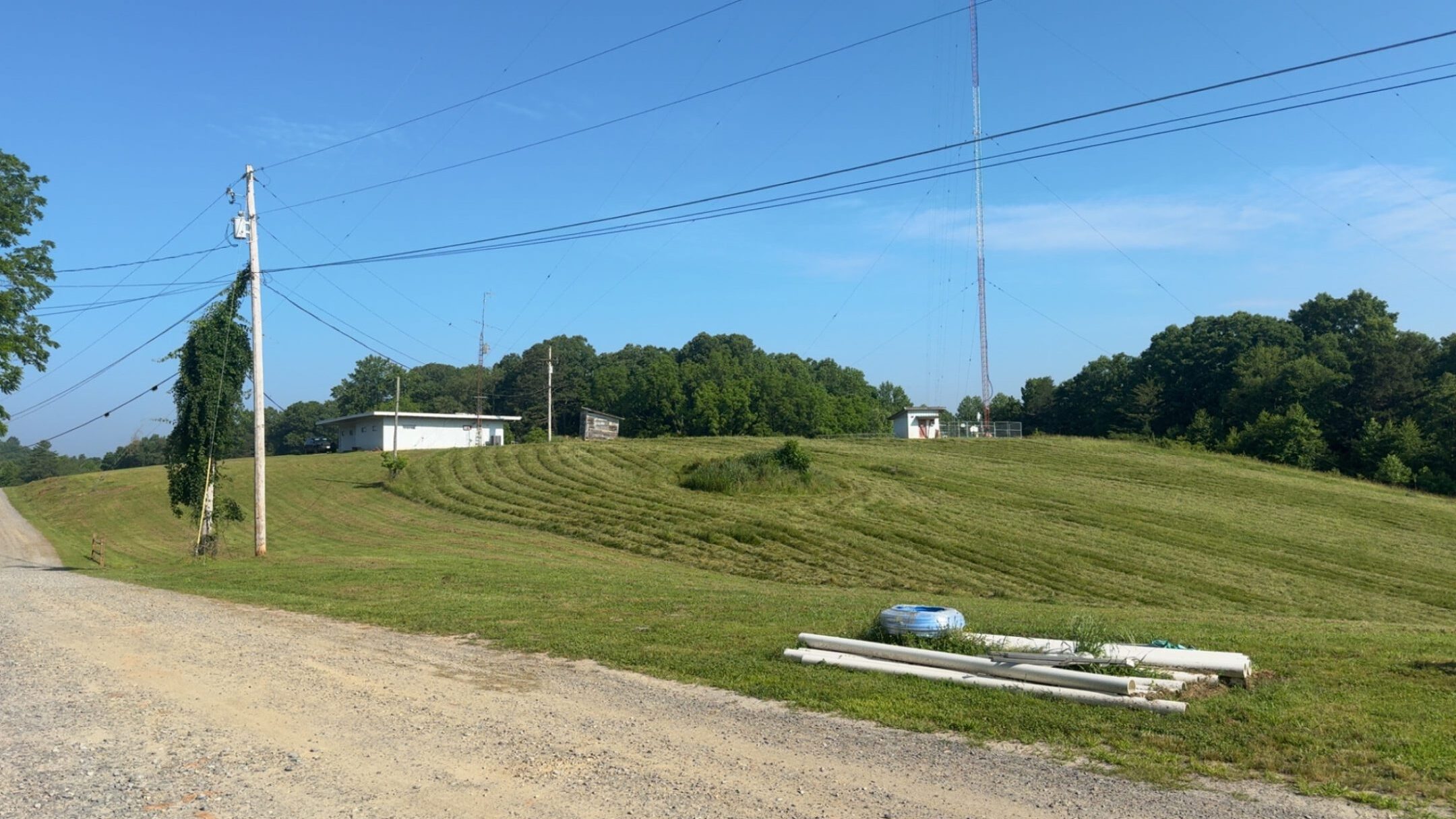 A rural landscape with green grass, power lines, and a clear blue sky.