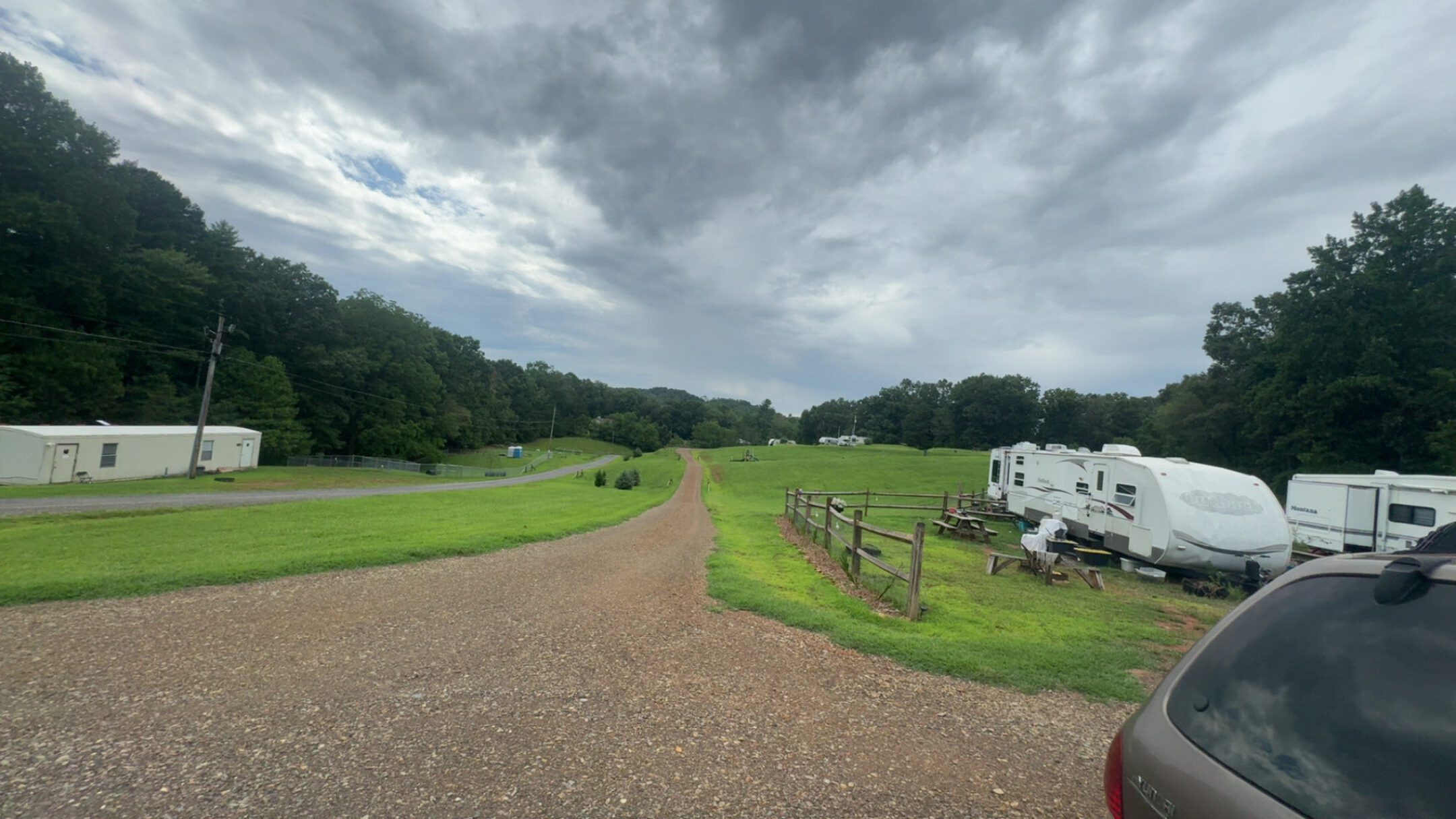 A cloudy sky over a green golf course and parking area.