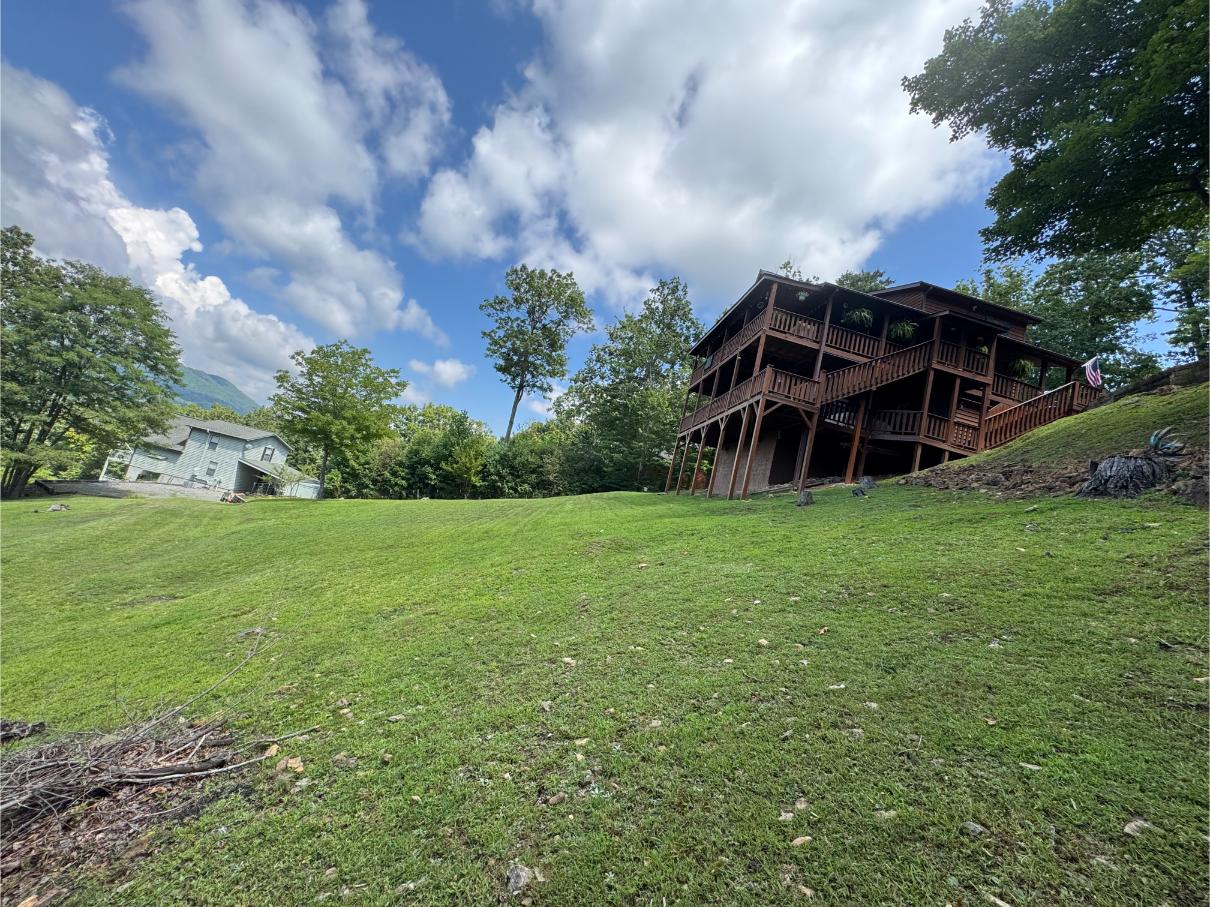 A wooden house on a grassy hill under a partly cloudy sky.